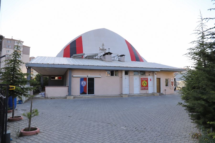 Tesis girişi, parabol çatılı saha ve önündeki otopark